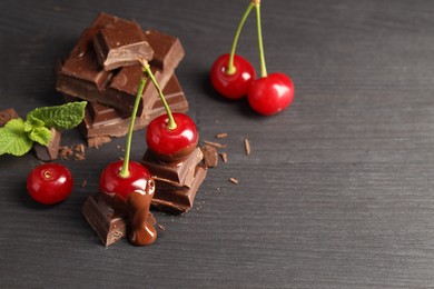 Fresh cherries with chocolate on grey wooden table, space for text