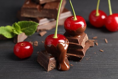 Photo of Fresh cherries with chocolate on grey wooden table, closeup