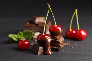 Photo of Fresh cherries with chocolate on grey wooden table, closeup