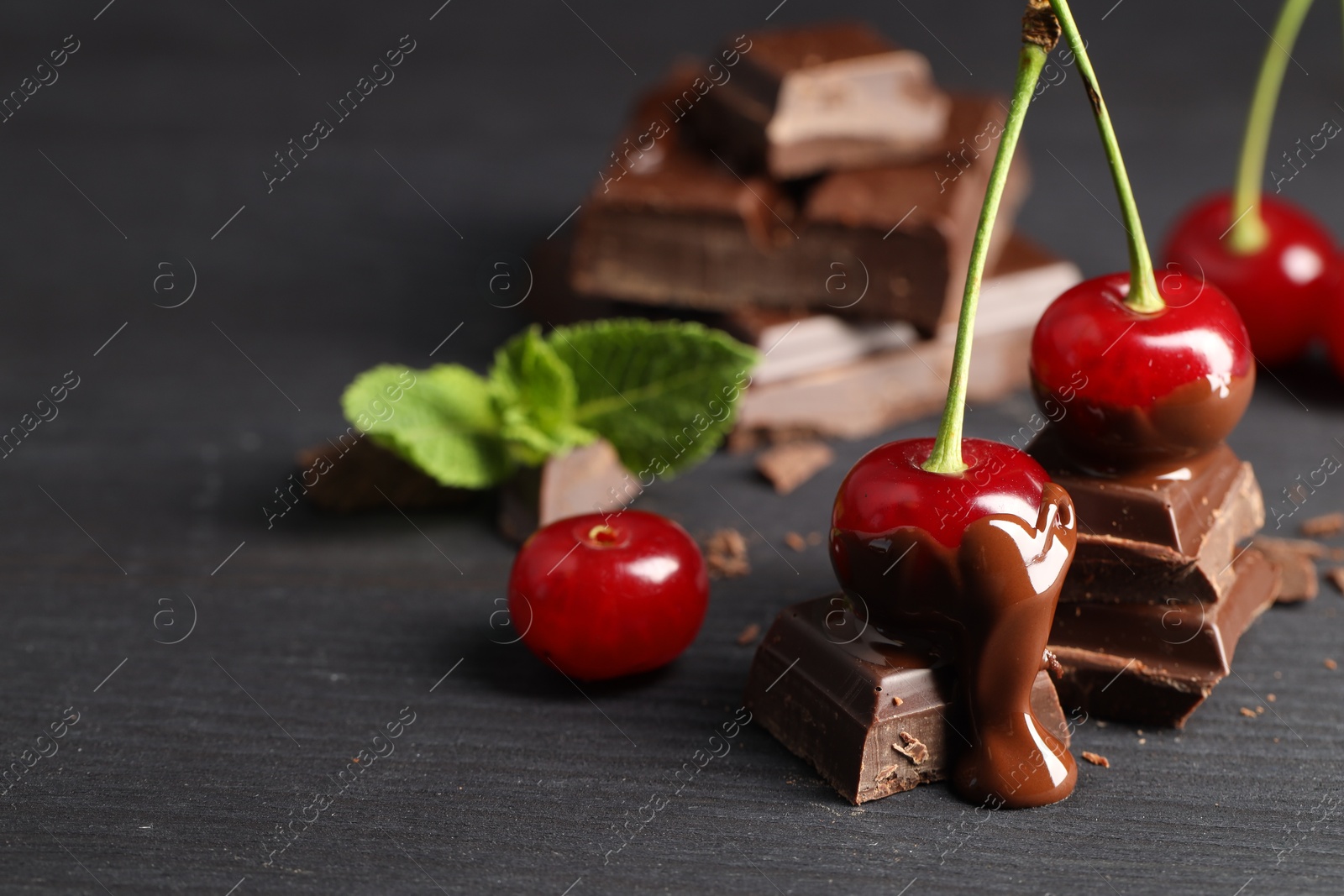 Photo of Fresh cherries with chocolate on grey wooden table, space for text