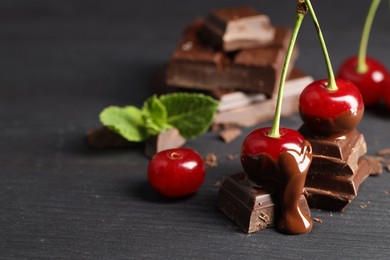 Fresh cherries with chocolate on grey wooden table, space for text