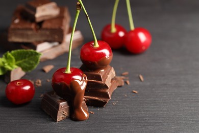 Fresh cherries with chocolate on grey wooden table, space for text