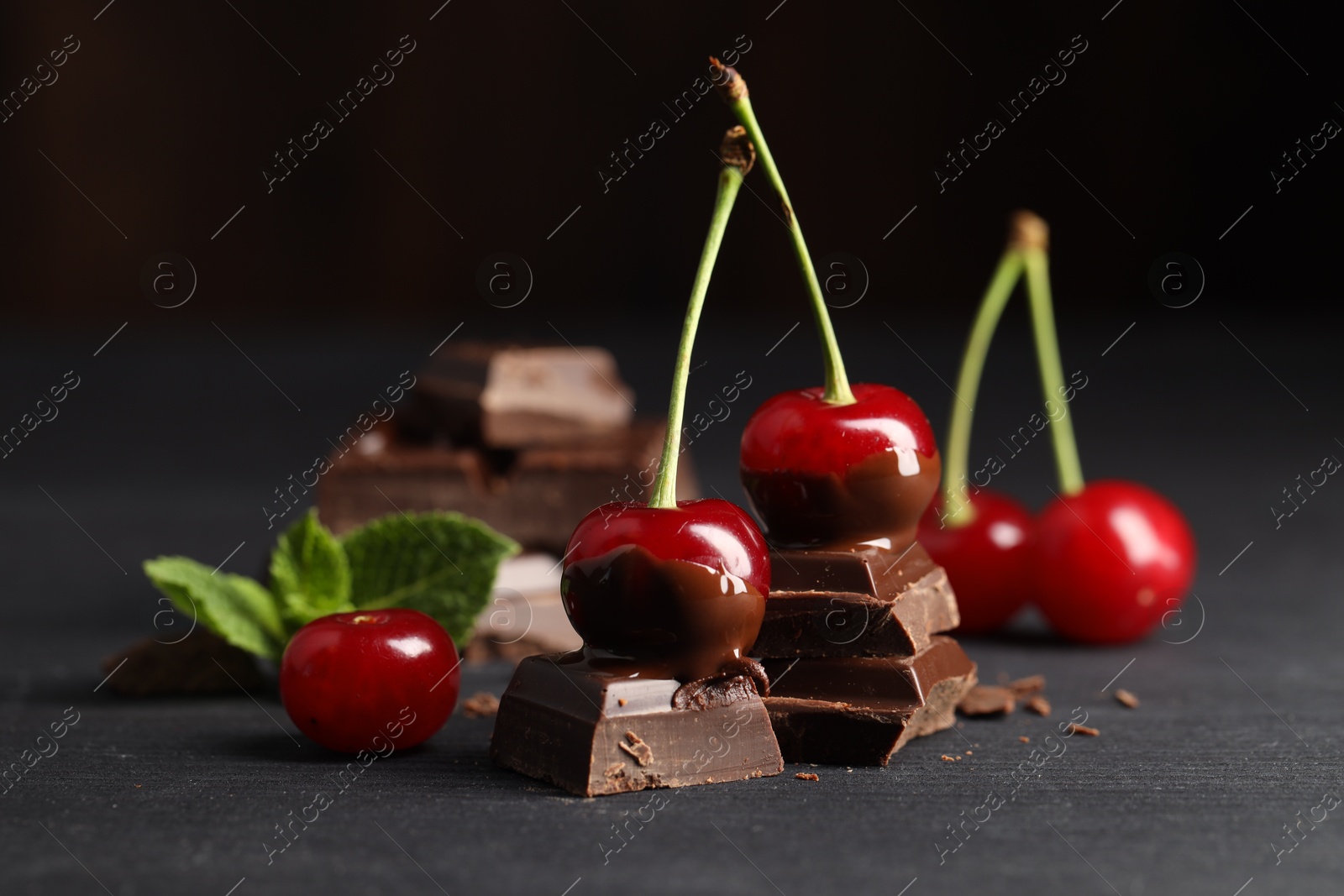 Photo of Fresh cherries with chocolate on grey wooden table, closeup