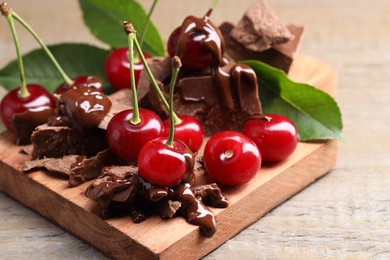 Fresh cherries with milk chocolate on wooden table, closeup