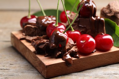 Photo of Fresh cherries with milk chocolate on wooden table, closeup