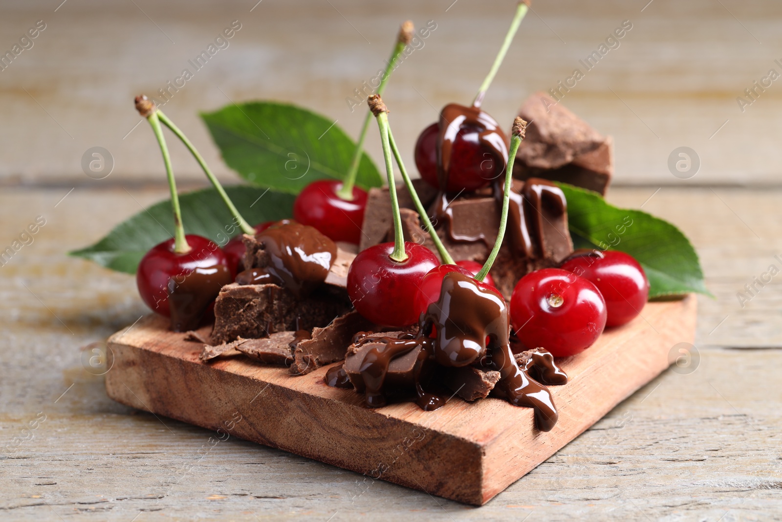 Photo of Fresh cherries with milk chocolate on wooden table, closeup