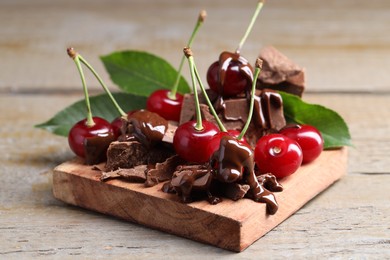 Fresh cherries with milk chocolate on wooden table, closeup