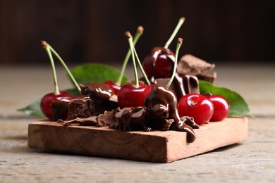 Photo of Fresh cherries with milk chocolate on wooden table, closeup