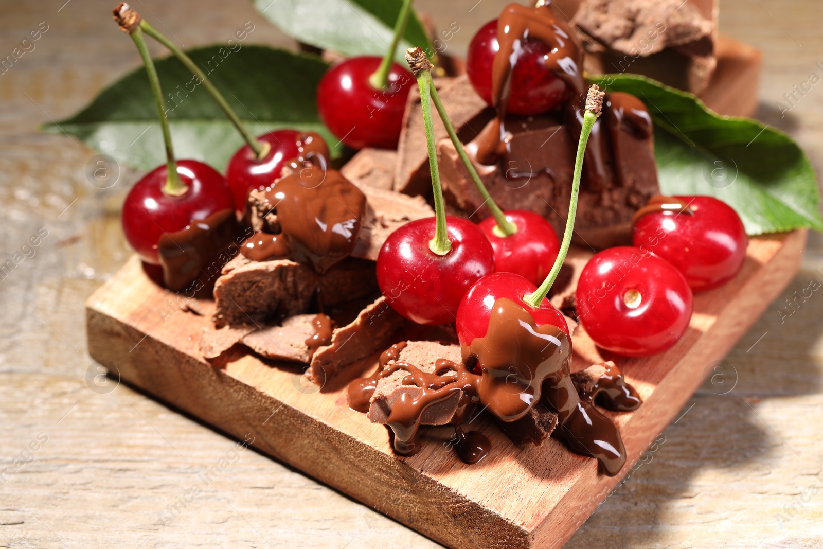 Photo of Fresh cherries with milk chocolate on wooden table, closeup