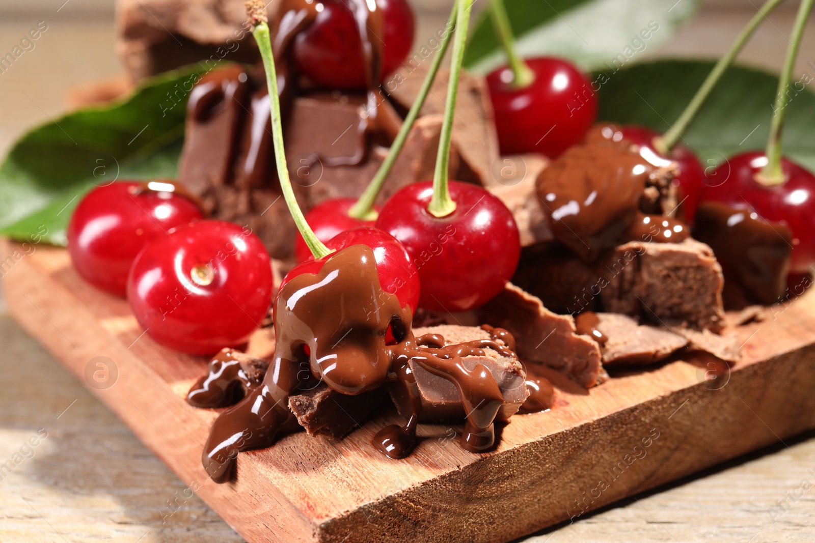 Photo of Fresh cherries with milk chocolate on wooden table, closeup