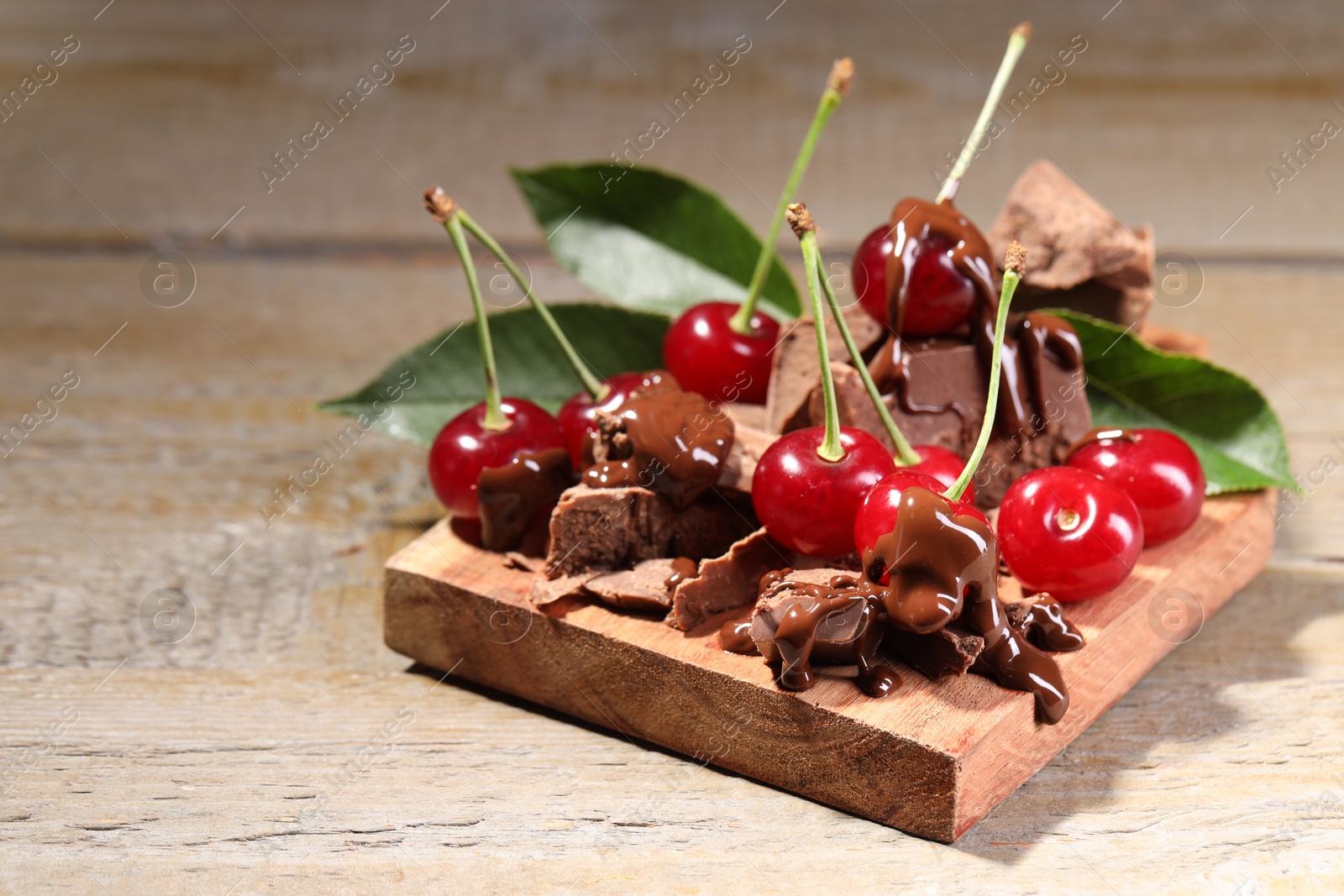 Photo of Fresh cherries with milk chocolate on wooden table