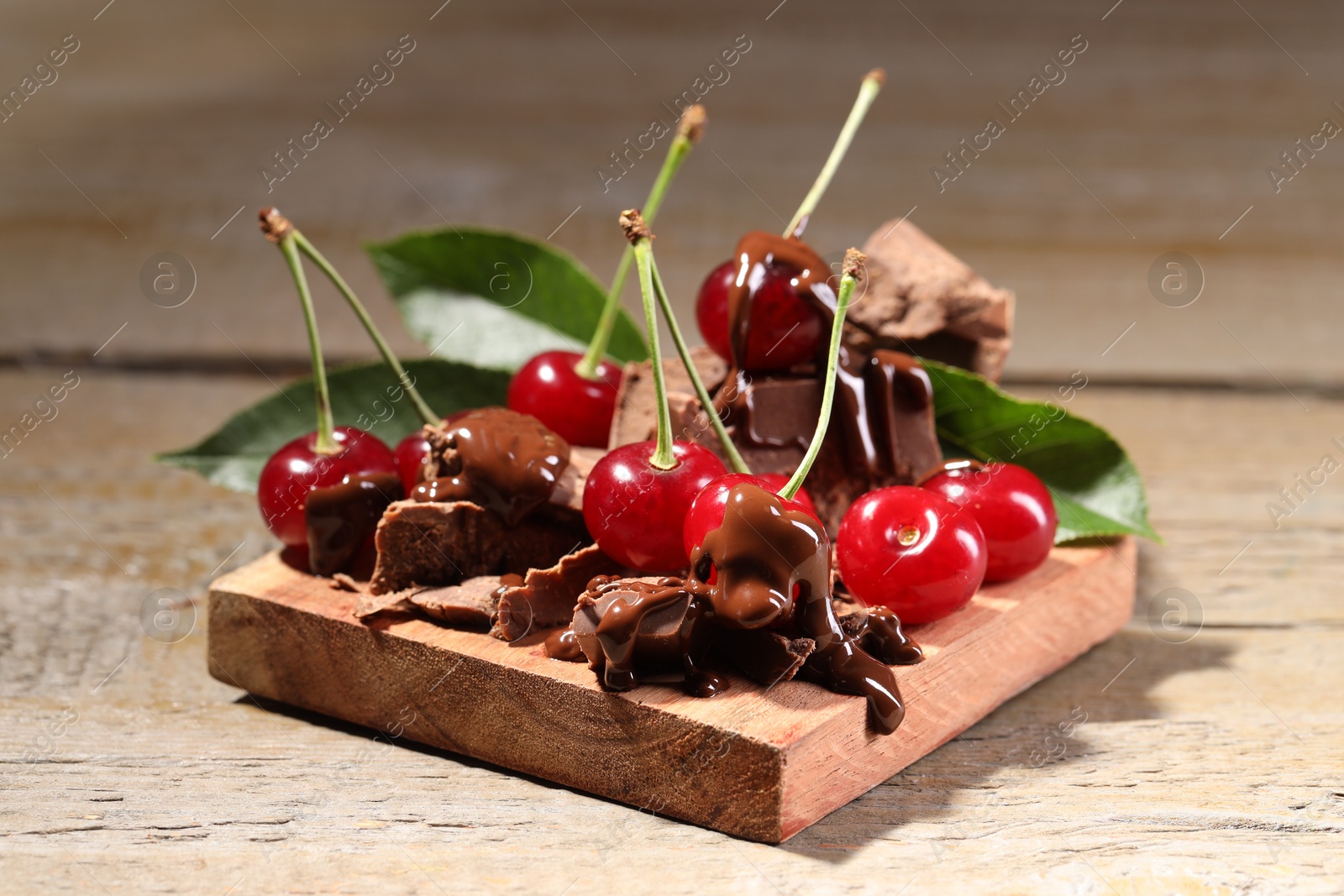 Photo of Fresh cherries with milk chocolate on wooden table