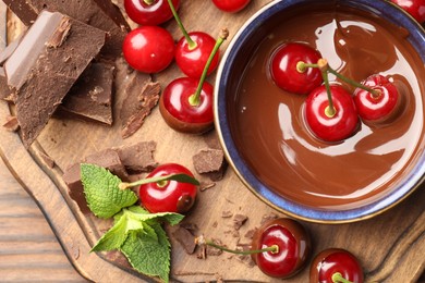 Fresh cherries with chocolate and mint on wooden table, flat lay