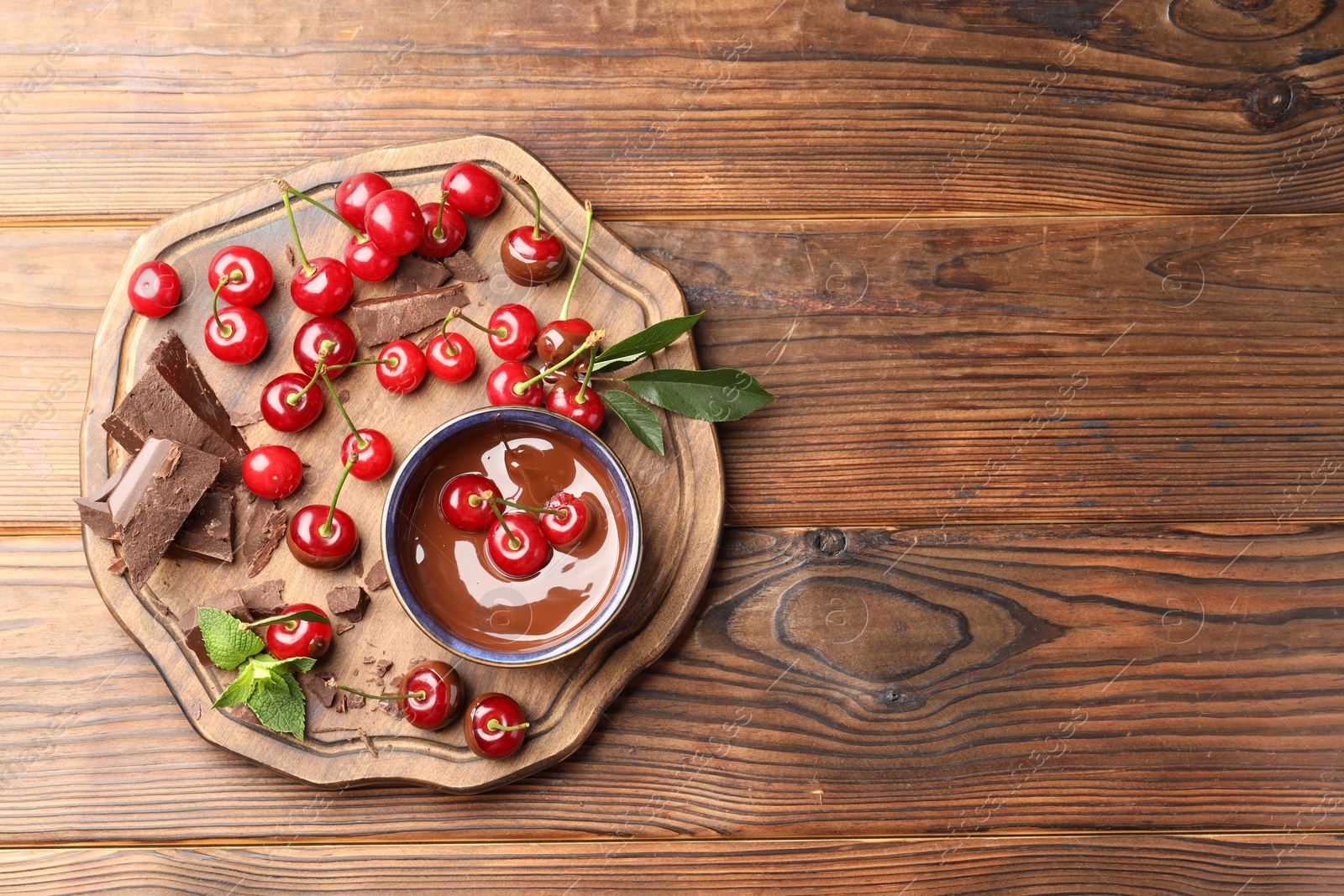 Photo of Fresh cherries with chocolate and mint on wooden table, top view. Space for text