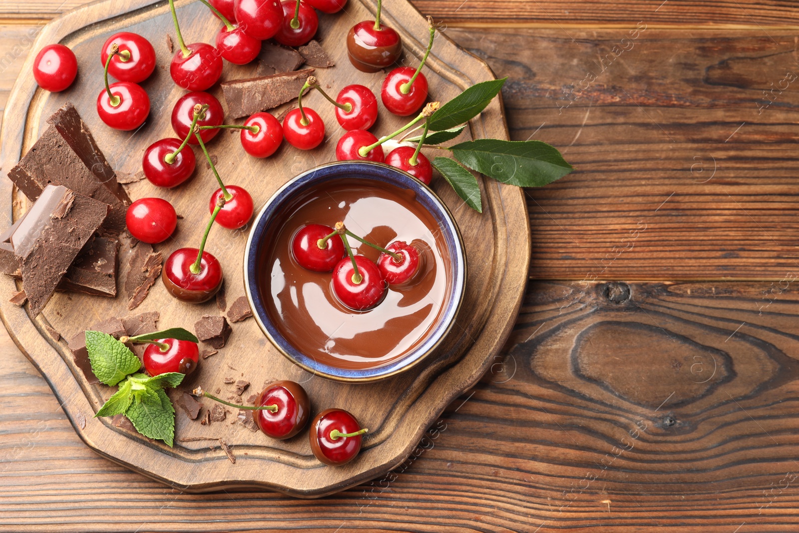Fresh cherries with chocolate and mint on wooden table, top view. Space for text Photo of Fresh cherries with chocolate and mint on wooden table, top view. Space for text