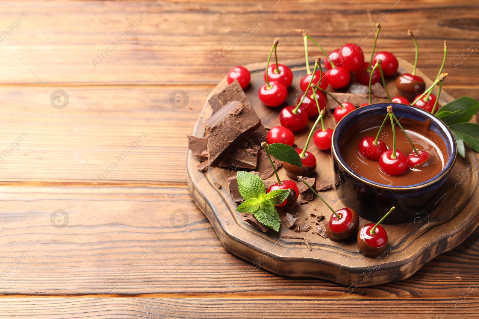 Photo of Fresh cherries with chocolate and mint on wooden table, space for text