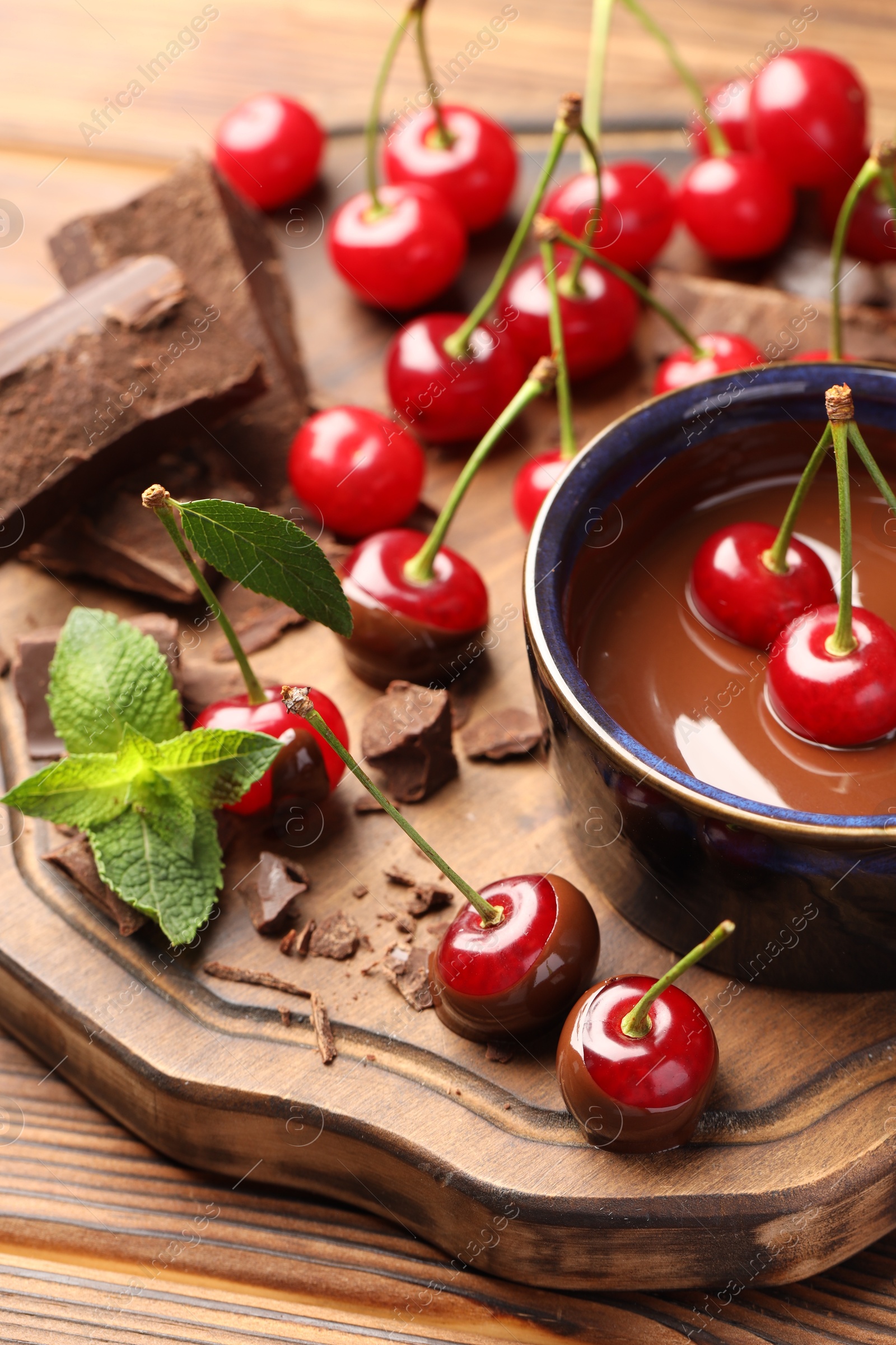 Photo of Fresh cherries with melted chocolate and mint on wooden table, closeup