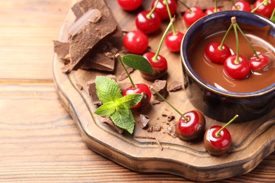 Fresh cherries with chocolate and mint on wooden table, closeup