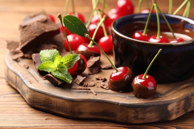 Photo of Fresh cherries with melted chocolate and mint on wooden table, closeup