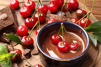 Photo of Fresh cherries with melted chocolate and mint on table, closeup