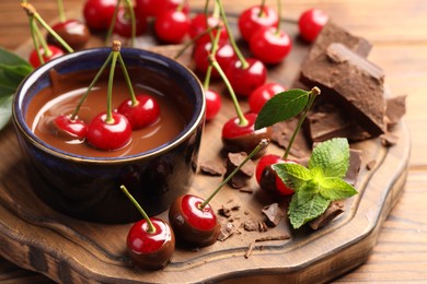 Photo of Fresh cherries with melted chocolate and mint on wooden table, closeup