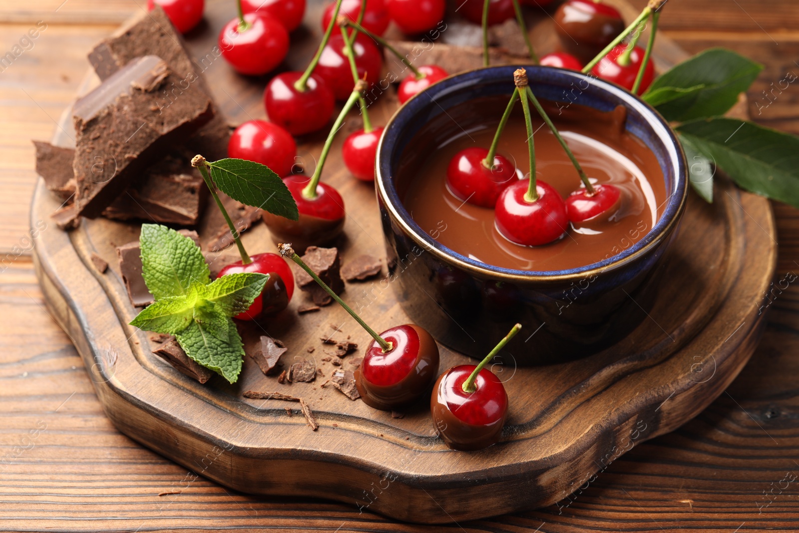 Photo of Fresh cherries with chocolate and mint on wooden table, closeup