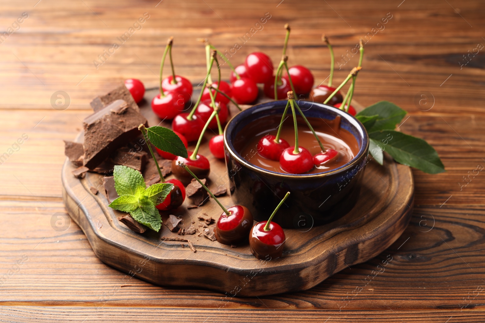 Photo of Fresh cherries with chocolate and mint on wooden table