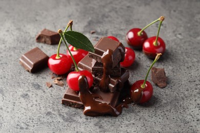 Photo of Fresh cherries with dark chocolate on grey textured table