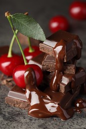 Fresh cherries with dark chocolate on grey textured table, closeup