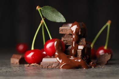 Fresh cherries with chocolate on grey textured table, closeup