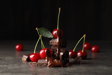 Fresh cherries with dark chocolate on grey textured table, closeup