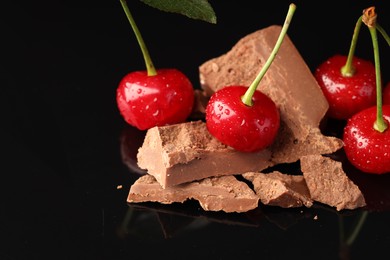 Fresh cherries with pieces of milk chocolate on black mirror surface, closeup