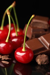 Fresh cherries with pieces of milk chocolate on black mirror surface, closeup