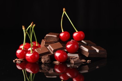 Fresh cherries with pieces of milk chocolate on black mirror surface