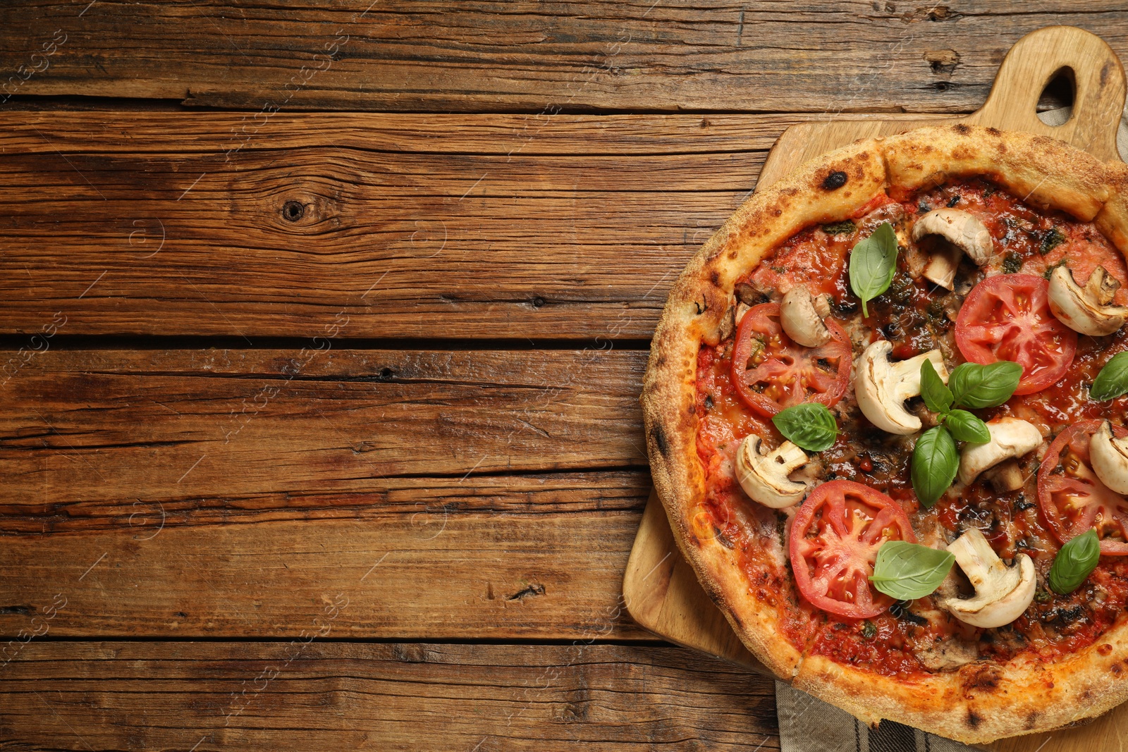 Photo of Tasty pizza with basil, mushrooms and tomato on wooden table, top view. Space for text