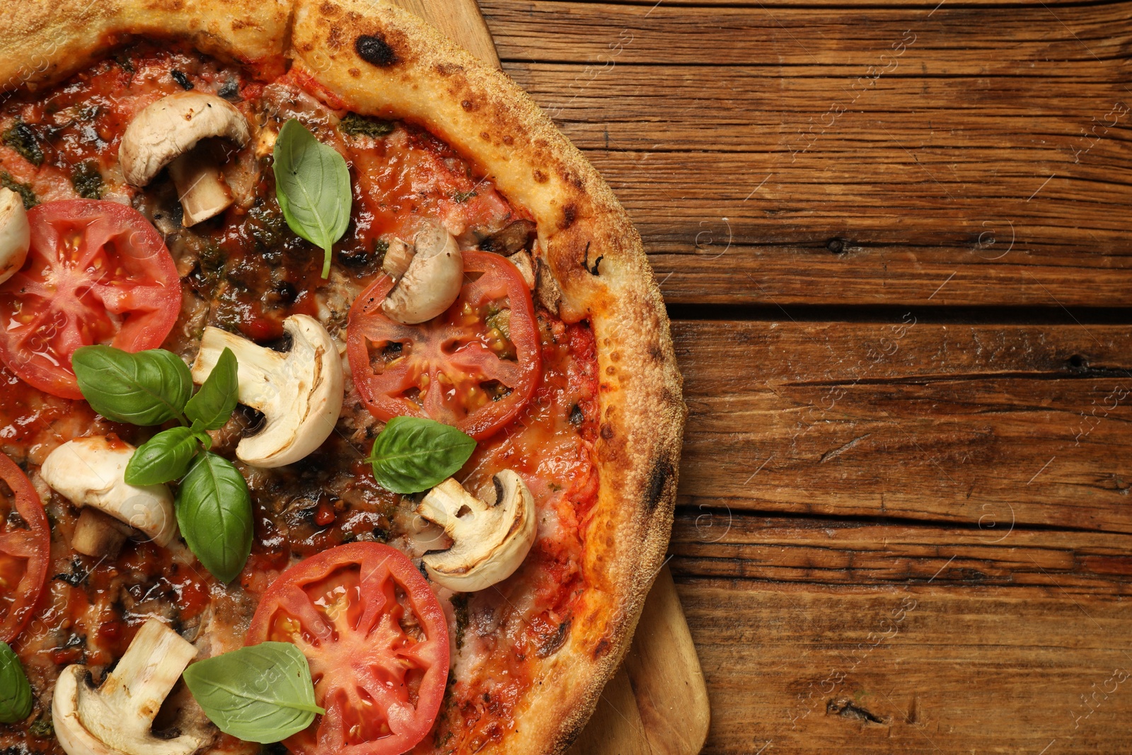 Photo of Tasty pizza with basil, mushrooms and tomato on wooden table, top view. Space for text