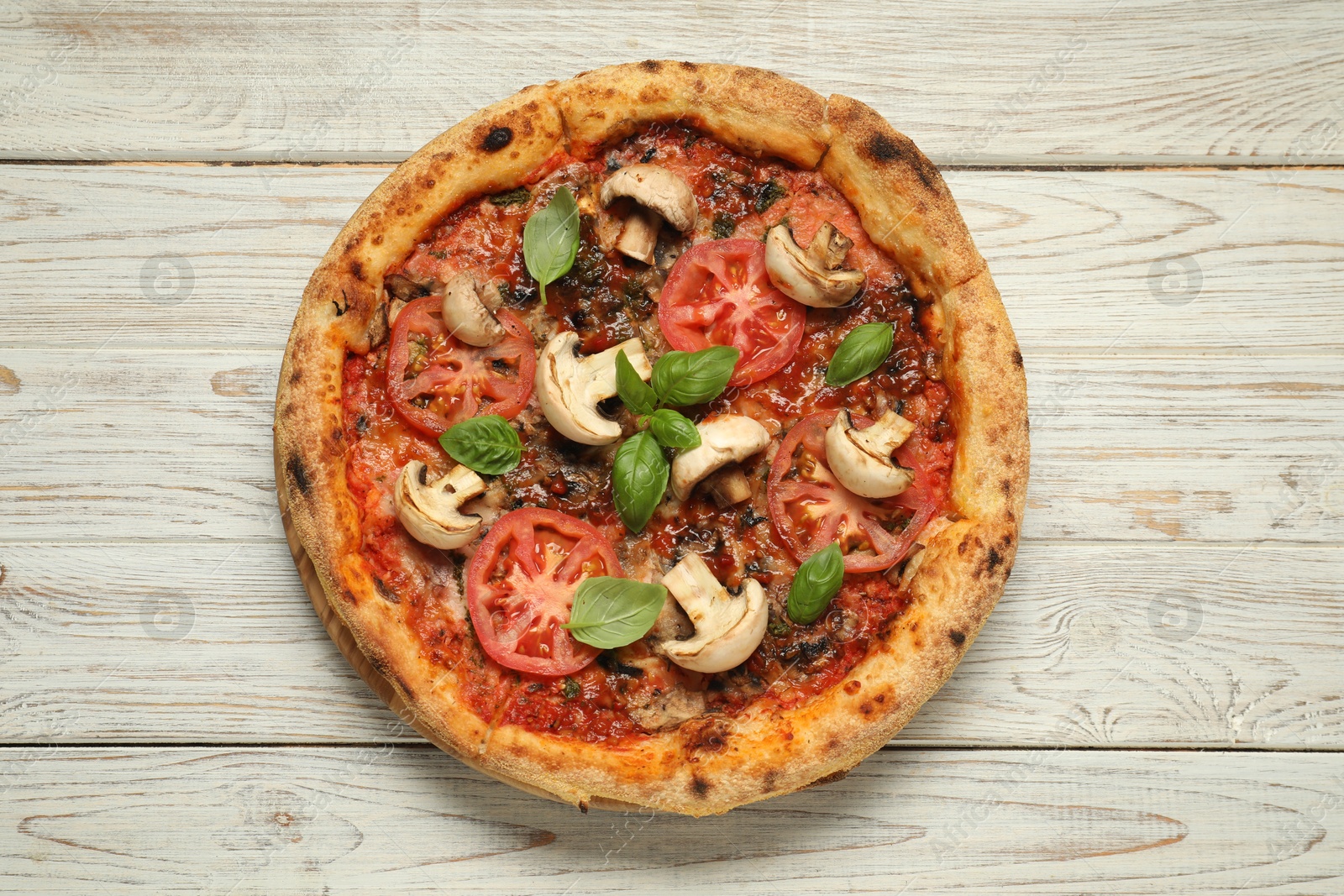 Photo of Tasty pizza with basil, mushrooms and tomato on wooden rustic table, top view