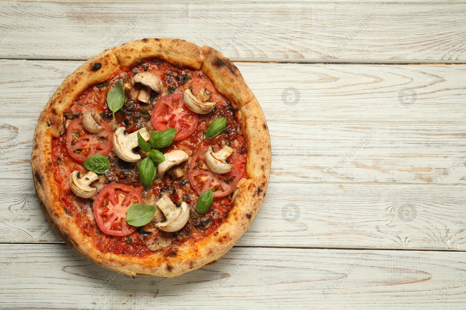 Photo of Tasty pizza with basil, mushrooms and tomato on wooden rustic table, top view. Space for text