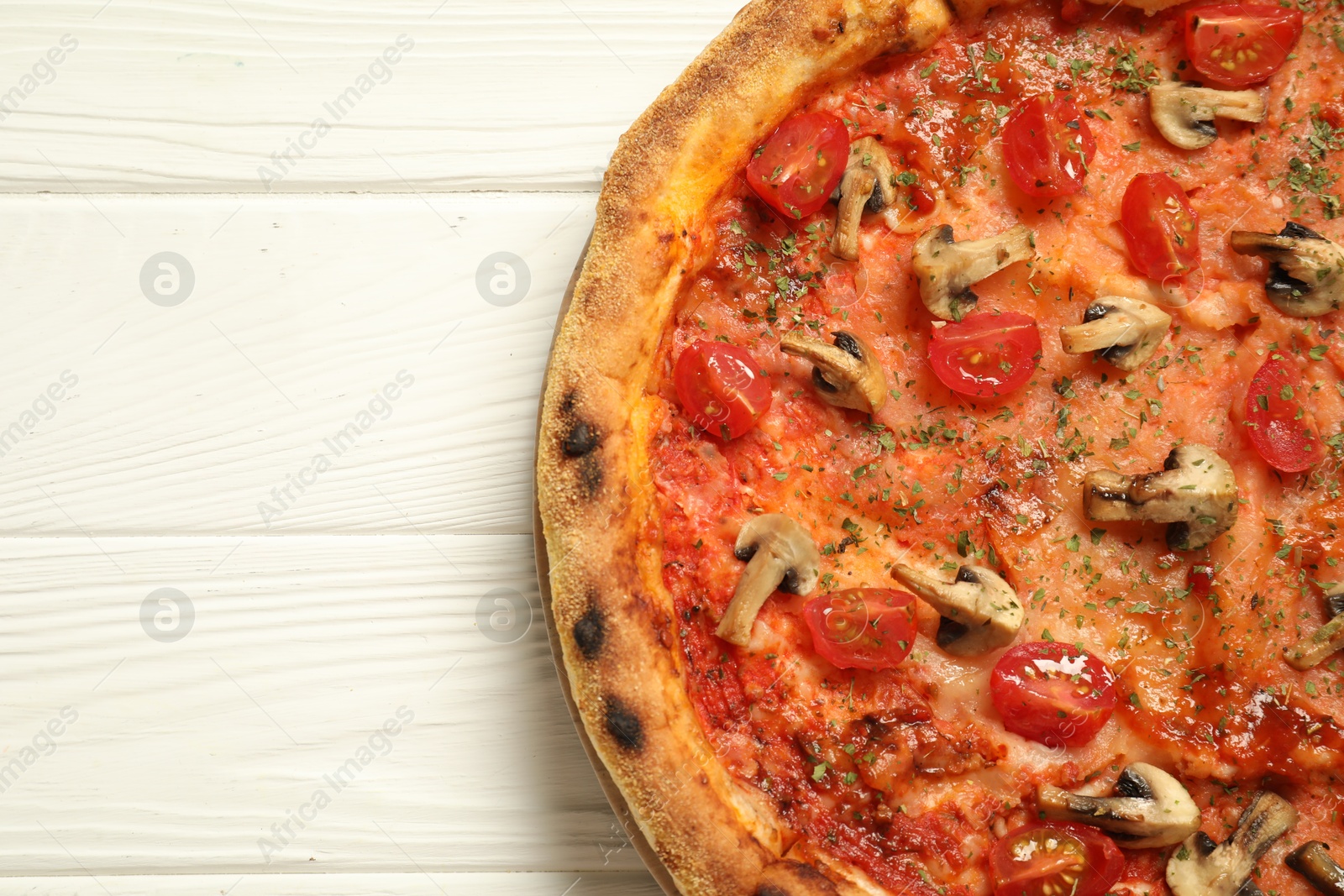 Photo of Tasty pizza with mushrooms, herbs and tomato on white wooden table, top view. Space for text