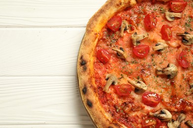 Tasty pizza with mushrooms, herbs and tomato on white wooden table, top view. Space for text