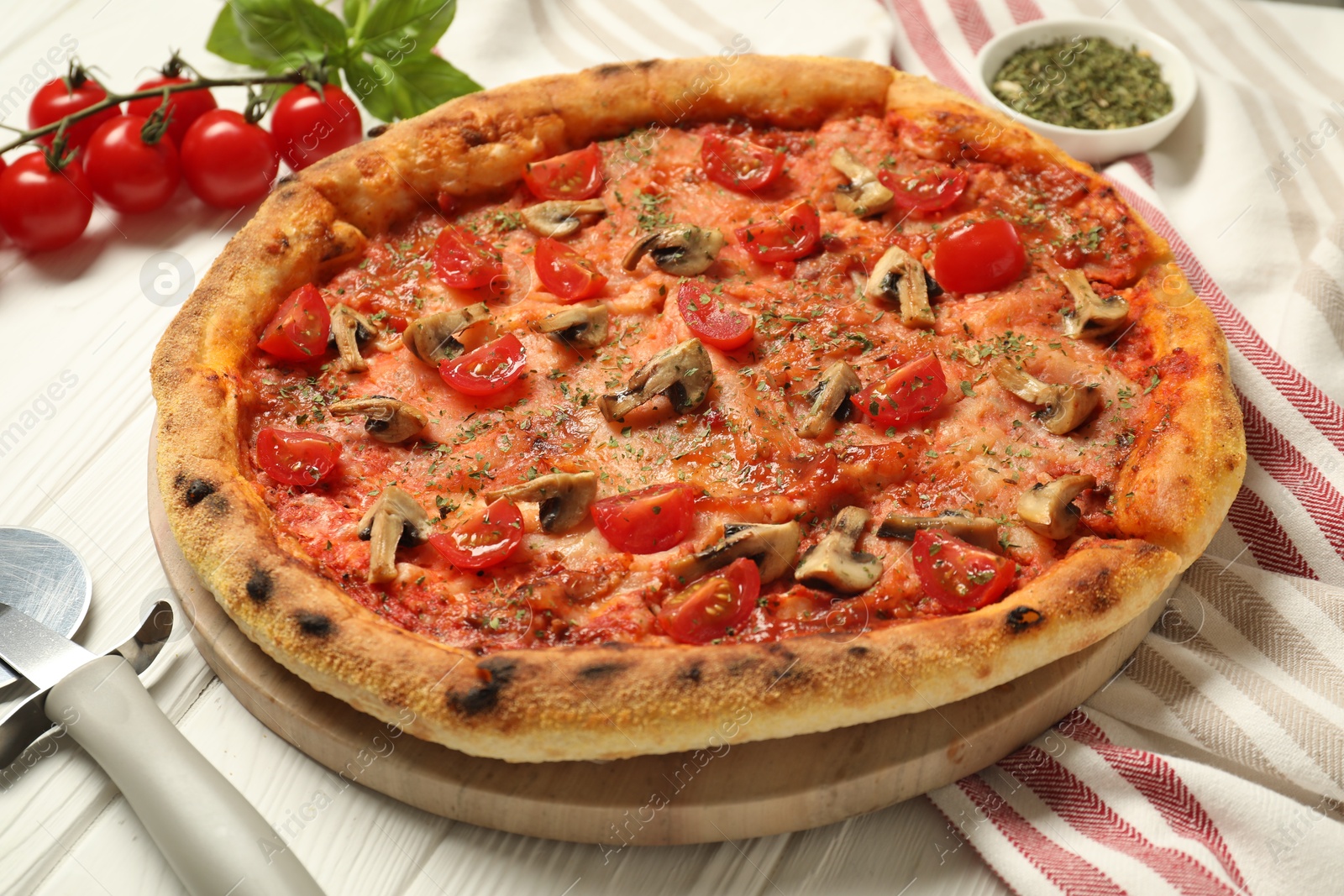 Photo of Tasty pizza with mushrooms, herbs and tomato on white wooden table, closeup