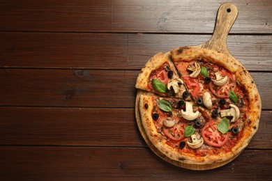 Tasty pizza with basil, mushrooms, olives and tomato on wooden table, top view. Space for text