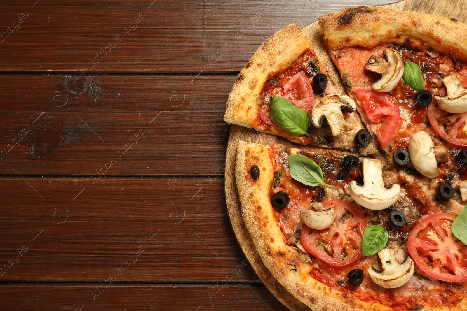 Photo of Tasty pizza with basil, mushrooms, olives and tomato on wooden table, top view. Space for text