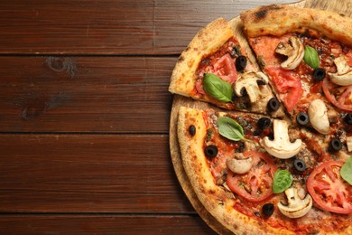 Photo of Tasty pizza with basil, mushrooms, olives and tomato on wooden table, top view. Space for text