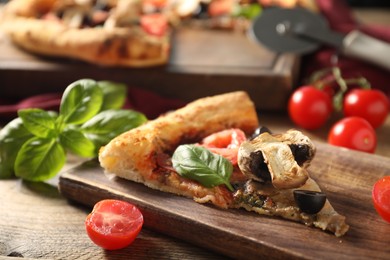 Photo of Piece of tasty pizza with basil, mushroom, olive and tomato on wooden table, closeup