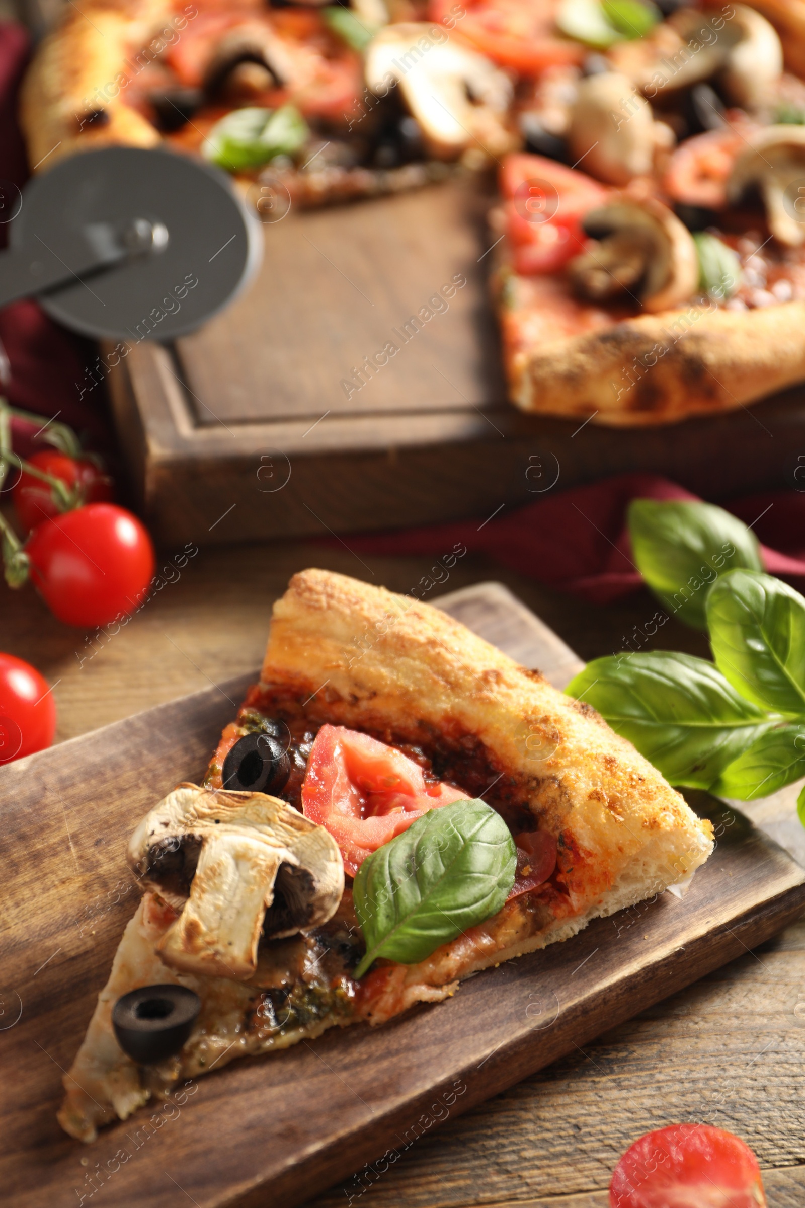 Photo of Piece of tasty pizza with basil, mushroom, olives and tomato on wooden table, closeup