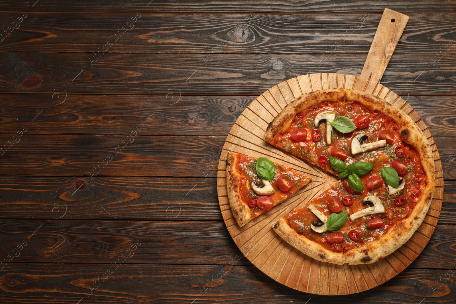 Photo of Tasty pizza with basil, mushrooms, chili pepper and tomato on wooden table, top view. Space for text