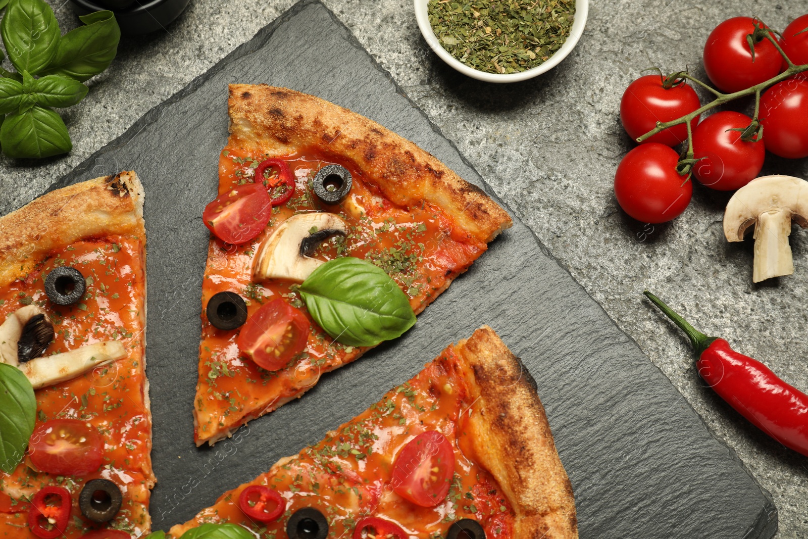 Photo of Tasty pizza with basil, olives and ingredients on grey textured table, flat lay