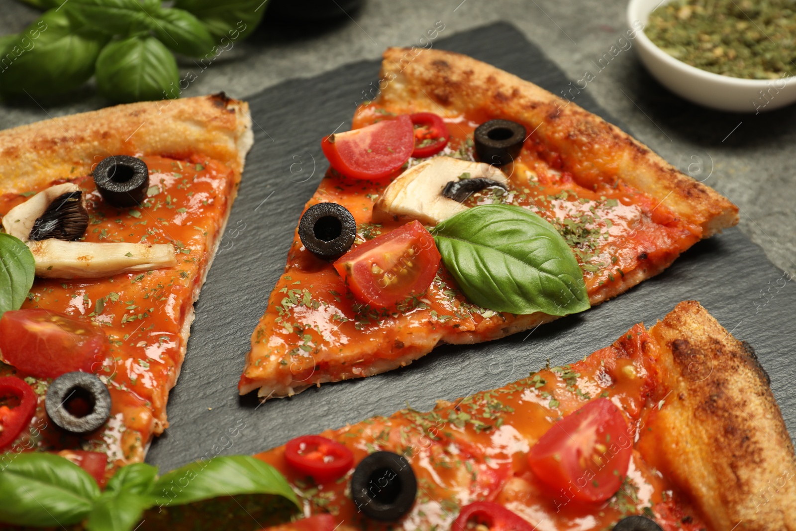 Photo of Tasty pizza with basil, olives and tomato on grey table, closeup