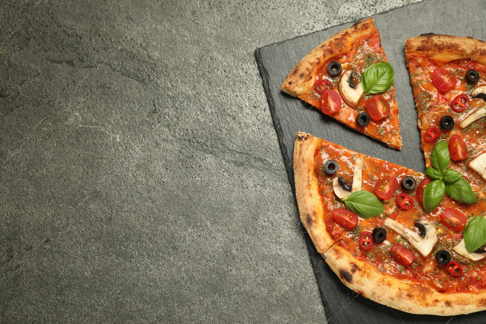 Photo of Tasty pizza with basil, olives and tomato on grey textured table, top view. Space for text